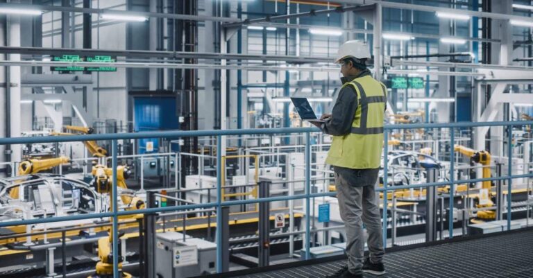 An Engineering overlooking the equipment and processes while looking at his laptop